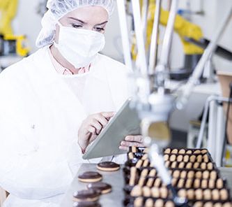 Woman in factory using tablet with robot handling cookies