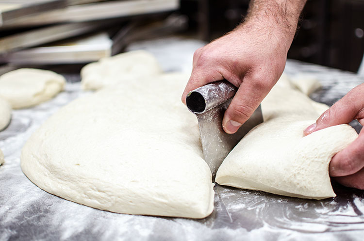 f2m-bbi-20-0-research-Male baker hands using kitchen utensil to divide dough prepared