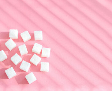 Refined sugar on pink background.Cubes of sweet and white sugar in geometricshape. Hard shadows.