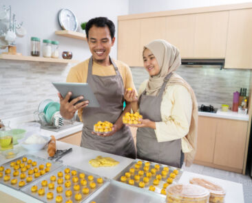 muslim couple business seller making food order at home together. nastar pineapple cake for eid mubarak celebration tradition snack
