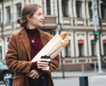 beautiful girl with baguettes and coffee walks around the city