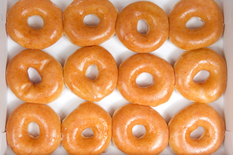 Top view flat lay of plain glazed donuts in a white box isolated
